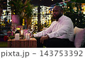 Close up of dejected boyfriend feeling stressed while waiting for his no show date. Lonely man waits alone for girlfriend in rooftop lounge beneath candlelight and urban lights 143753392