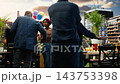 People revealing surprise birthday party for woman with eyes covered, friends gathered around rooftop barbecue table. Celebration and shared social experience. 143753398