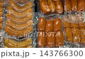 Assorted packaged sausages arranged in rows, showing varied shapes, sizes, and golden brown colors under clear plastic for food retail, grocery shopping, packaging, and culinary content video Assorted packaged sausages arranged in rows, showing varied shapes, sizes, and golden brown colors under clear plastic for food retail, grocery shopping, packaging, and culinary content video 143766300