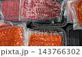 Packaged sliced cured meats arranged in transparent trays, featuring orange chorizo and marbled salami on woven black display surface, suitable for grocery, deli, food marketing, and culinary video Packaged sliced cured meats arranged in transparent trays, featuring orange chorizo and marbled salami on woven black display surface, suitable for grocery, deli, food marketing, and culinary video 143766302
