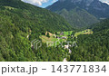 Scenic drone shot of isolated traditional farm standing on bright green pasture slope surrounded by dark evergreen forest in Slovenia mountains. 143771834