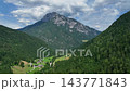 Scenic drone shot of isolated traditional farm standing on bright green pasture slope surrounded by dark evergreen forest in Slovenia mountains. 143771843