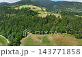 Scenic drone shot of isolated traditional farm standing on bright green pasture slope surrounded by dark evergreen forest in Slovenia mountains. 143771858