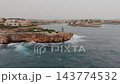 Overwater Drone Sweep Along Mallorca Shoreline, With Rugged Rock Ledge And Distant Houses. 143774532