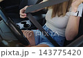 Woman driver fastening seat belt before driving a car 143775420