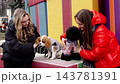 Dogs play with their owners at a colorful outdoor park in winter 143781391