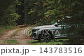 Silver SUV Parked on Narrow Dirt Road in Forest 143783516