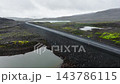 Narrow road cutting diagonally through foggy volcanic plateau with reflective pools, moss patches, misty ridgelines, and overcast rocky terrain textures 143786115