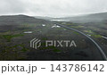 Narrow road cutting diagonally through foggy volcanic plateau with reflective pools, moss patches, misty ridgelines, and overcast rocky terrain textures 143786142