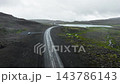 Narrow road cutting diagonally through foggy volcanic plateau with reflective pools, moss patches, misty ridgelines, and overcast rocky terrain textures 143786143
