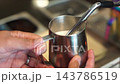 Barista Steaming Milk with Machine Wand in Stainless Steel Pitcher 143786519