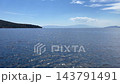 A distant boat sailing across a calm, sparkling blue sea past a rocky island under a clear sky near Bodrum, Turkey. High quality 4k footage 143791491