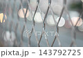 The blurred image of traffic and city lights visible through the wire mesh. 143792725