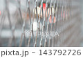 The blurred image of traffic and city lights visible through the wire mesh. 143792726