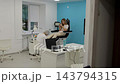 Pedicurist works on womans feet during calm salon appointment. Seated client relaxes in specialized chair, while manicure supplies and equipment are arranged around treatment area. 143794315