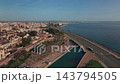 Aerial View Of Mallorca Waterfront Showing Coastal Road, Harbor Canal, Calm Bay, City Skyline, Urban Buildings, Marina, Promenade, And Warm Morning Sunlight 143794505