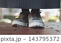 The feet of a person standing still in sneakers 143795372