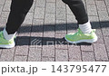 The feet of a person walking while wearing sneakers 143795477