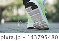 The feet of a person walking while wearing sneakers 143795480
