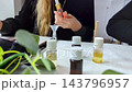 Woman making custom perfume during a creative workshop. She mixes essential oils with a dropper and funnel to create a unique fragrance.  143796957