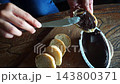Top Down View Spreading Dark Chocolate Paste on Baguette Bread Slice 143800371