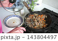 A woman fries beef liver with onions and carrots in a kitchen. She uses oil to cook the liver, creating a nutritious dish rich in iron 143804497