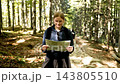Young woman hiker holding and reading paper map in forest 143805510