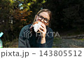 Hungry woman hiker eating a sandwich on a forest trail 143805512