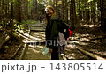 Woman hiker walking on a wooden boardwalk trail in forest 143805514