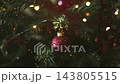 Close-up of a decorated Christmas tree with red baubles and glowing lights 143805515