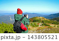 Woman hiker from behind taking photos of mountain landscape 143805521