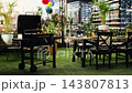 Empty rooftop event space prepared for BBQ entertaining with grill, beer bottles and food on dining table. Chairs and party decorations offering urban outdoor setting for cooking and leisure. 143807813