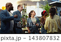 Friends talk and gesture at rooftop barbecue party beside grill and balloons, representing lively conversation, social connection, friendship and relaxed group leisure. 143807832