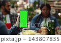 Vertical green screen isolated mockup on mobile phone at rooftop party, filling foreground while group toasts behind. Editable screen replacement in social lifestyle setting. 143807835