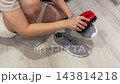 Woman cleaning athletic shoes before exercise, Female athlete readying sneakers for gym run with brush, Athlete using brush to clean sports shoes before exercise in minimalist setting 143814218