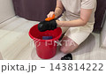 Caucasian woman promptly tidies her boots, Efficient woman refreshes her shoes with orange cloth, Caucasian female promptly cleans and refreshes her black boots using bright orange cloth 143814222