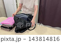 Female organizes her travel essentials, Woman meticulously packs clothes and accessories carefully, She systematically gathers and arranges clothing and necessities for her upcoming journey 143814816