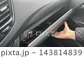 Car interior with routine travel details. Inside vehicle showing typical travel accessories and actions. Detailed view of car interior with passenger retrieving objects from glove compartment 143814839