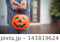Hands hold a Halloween pumpkin bucket outside a home 143819624
