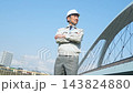 A male worker gazes into the distance from a bridge. Construction, engineering, infrastructure, inspection, testing, maintenance, upkeep, safety, repair. 143824880