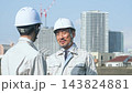 A group of male workers talking in front of a city. Construction, engineering, site, engineers, building maintenance, worksite, teamwork. 143824881