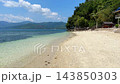 Idyllic tropical coastline with white sand turquoise sea palms wooden hut and lush green hills on sunny day 143850303