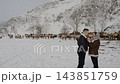 Couple in Snowy Mountains with Herd of Maral Deer in Background. 143851759