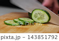 Fresh Cucumber Sliced with Kitchen Knife on Cutting Board. 143851792