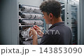 Male Data Center Engineer Connecting RJ45 Ethernet Cables to Network Switch 143853090
