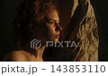 Woman Exploring Her Inner World in Warm Cinematic Light Surrounded by Crumpled Paper 143853110