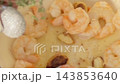 Shrimp cooking with garlic and herbs in a pale blue pan 143853640