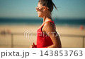 Woman jogging beside the sea, side view in a red top and white skirt 143853763