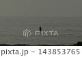 Two people riding boards across calm coastal water 143853765