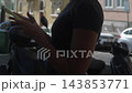 Side view of a woman using her smartphone beside a city street 143853771